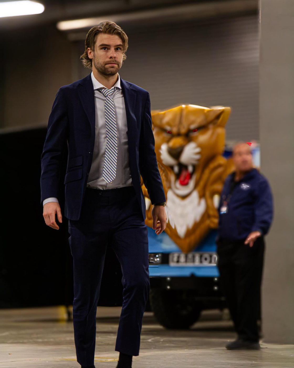 A Florida Panthers player in a suit arriving past the team mascot