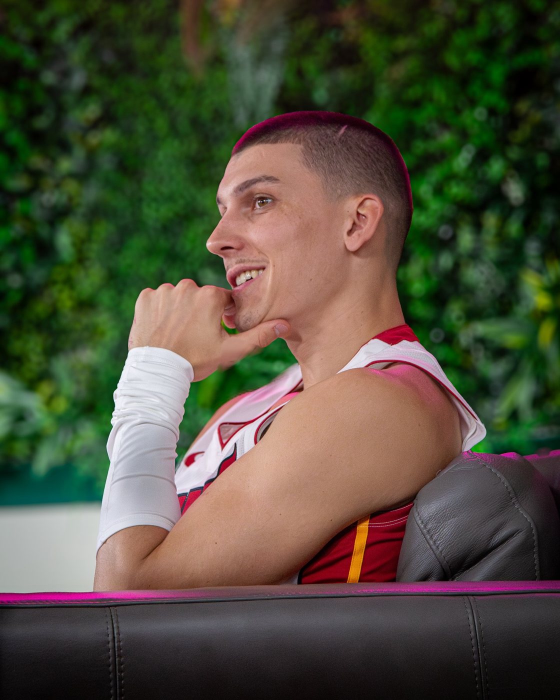 Tyler Herro smiling in profile in front of a green wall