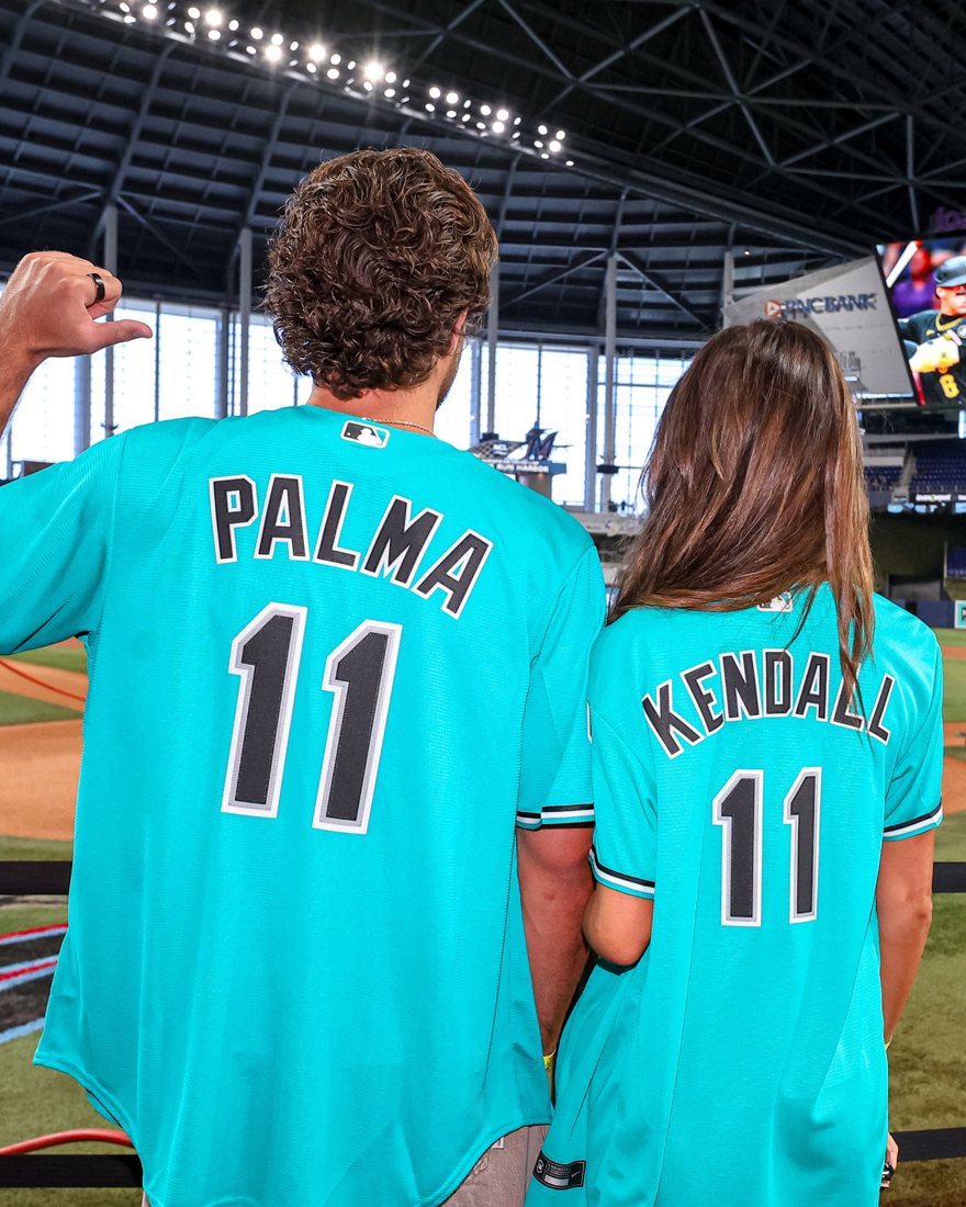 TJ Palma and Iris Kendall from behind in teal Marlins jerseys with their names and number 11, looking out at loanDepot park