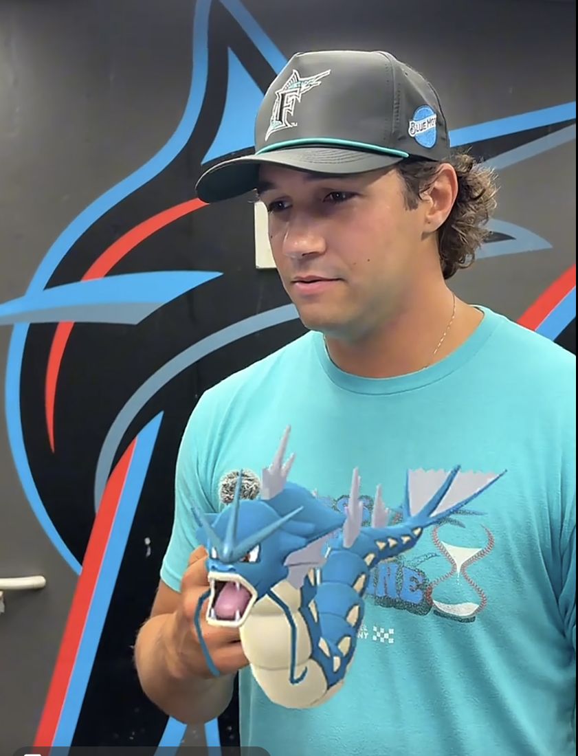 A Marlins player holding a Gyarados toy in the clubhouse