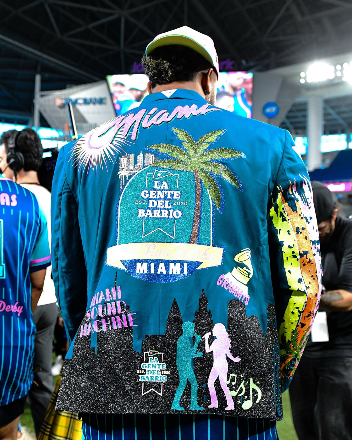 A custom glitter jacket reading La Gente del Barrio Miami at the celebrity softball game