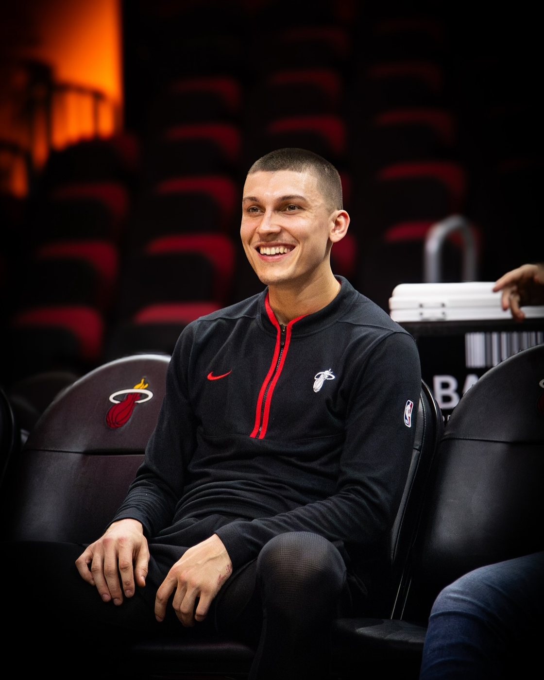 Tyler Herro smiling courtside in a Heat jacket